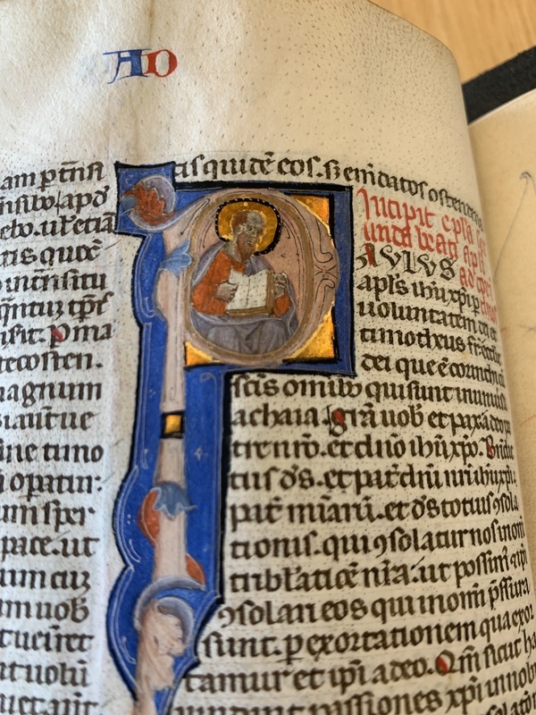 St. Paul reading a book inside a historiated initial of the letter "p"